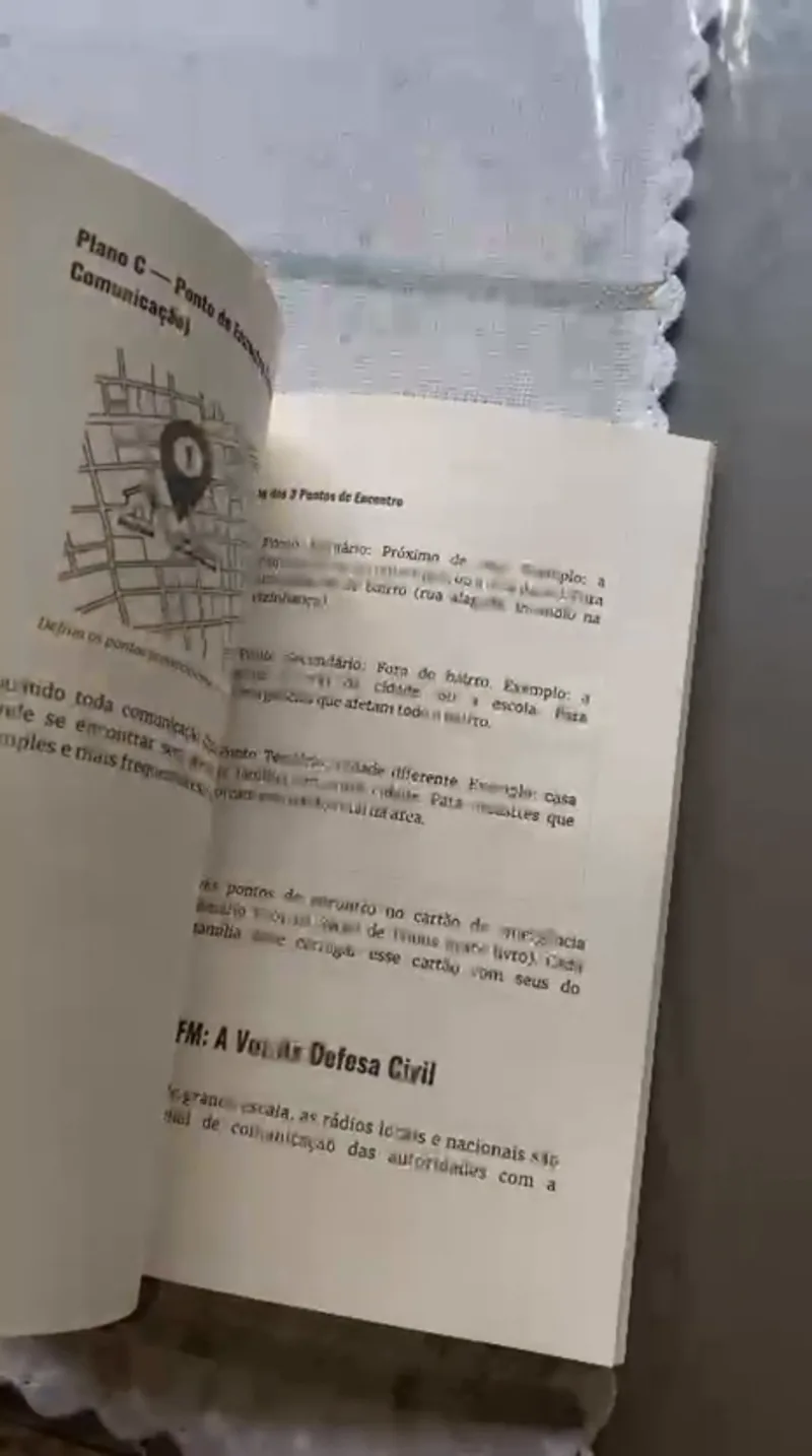 Página do livro aberta no plano de comunicação da família, com um mapa do ponto de encontro